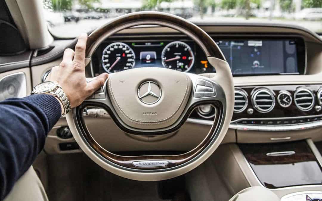 Man with left hand on steering wheel of a car